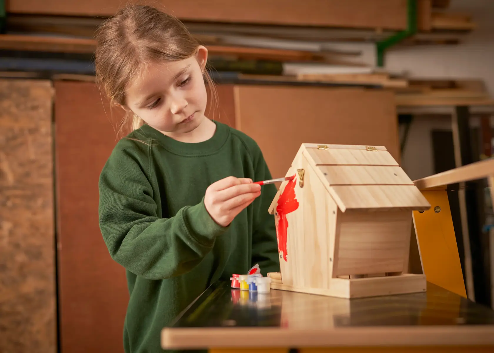STANLEY K020-SY photography of child painting wooden birdhouse with red paint at table.