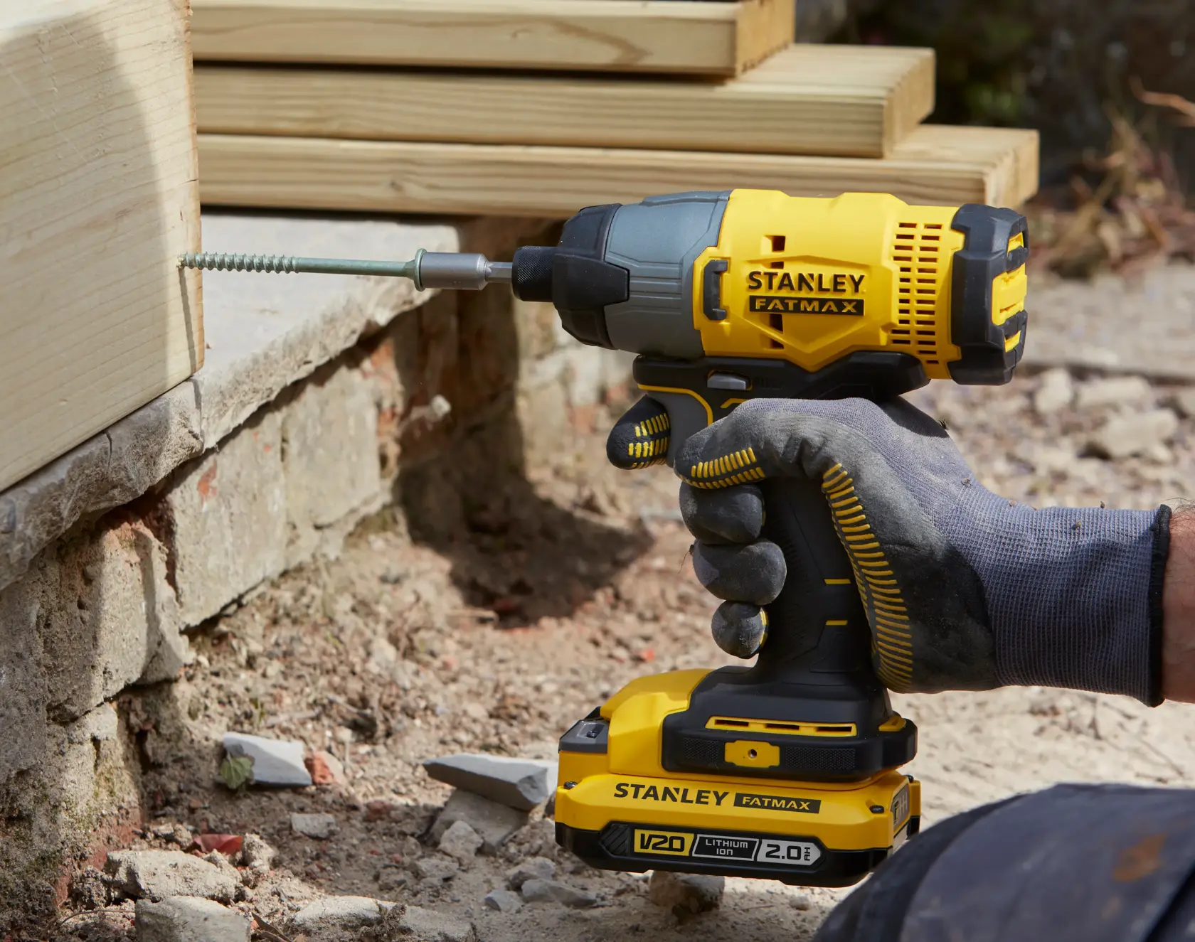STANLEY SFMCF800D1K impact driver, yellow and black, being used to drill into wood outdoors.
