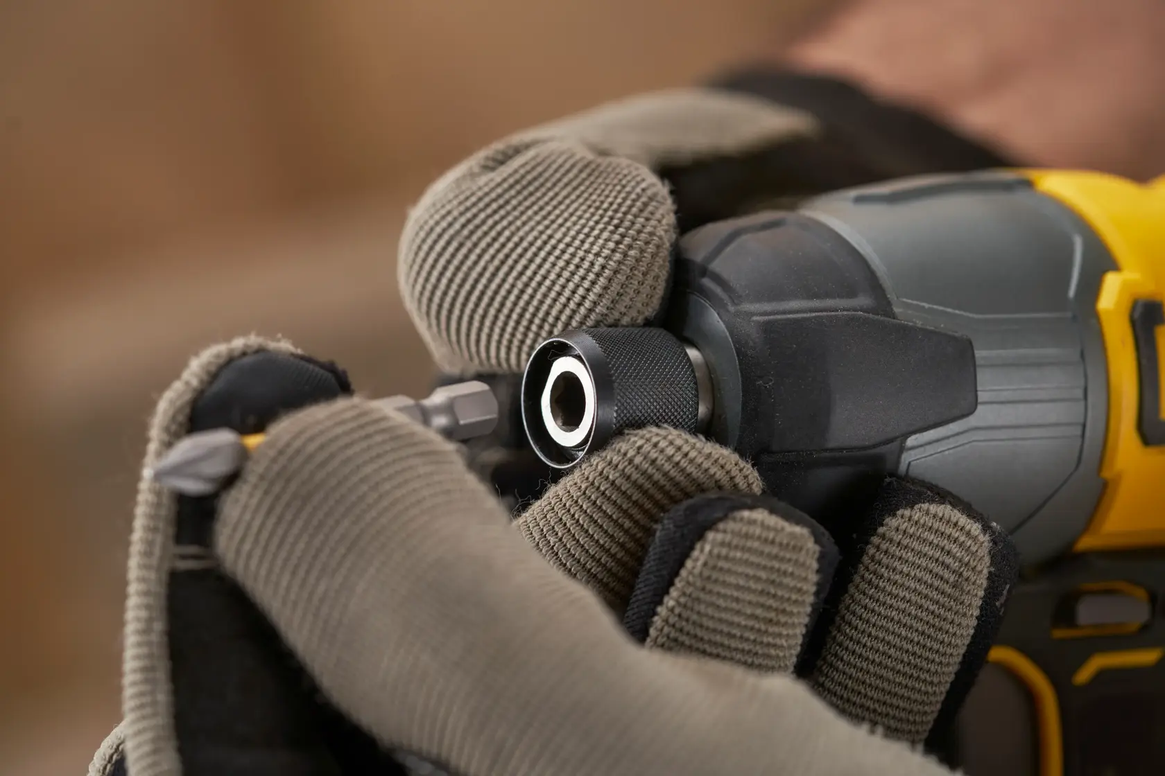 Gloved hands inserting a bit into a Stanley cordless impact driver, close-up view of tool and details.