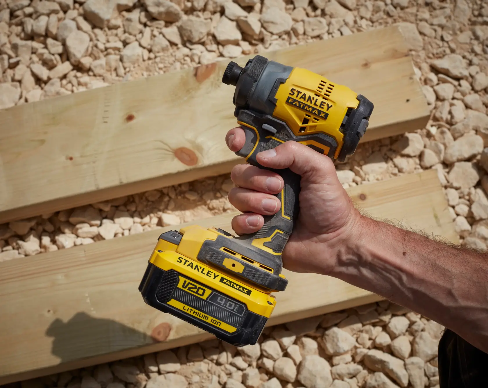 Stanley SFMCF810M1K cordless impact driver held in hand, yellow and black color, outdoor setting.
