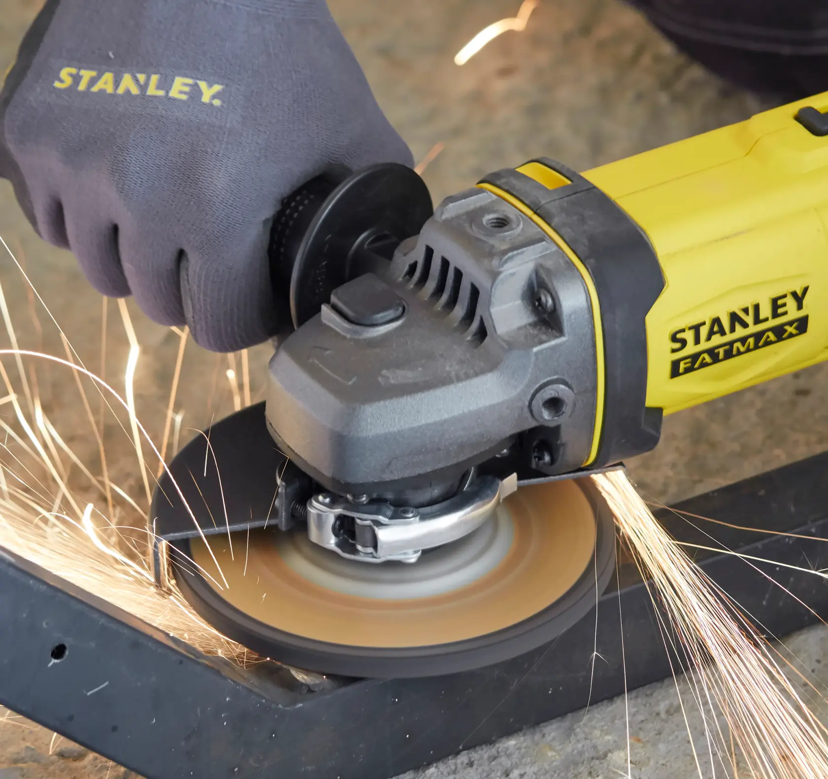 STANLEY SFMCG400M1K angle grinder in use, emitting sparks while grinding metal, close-up view.