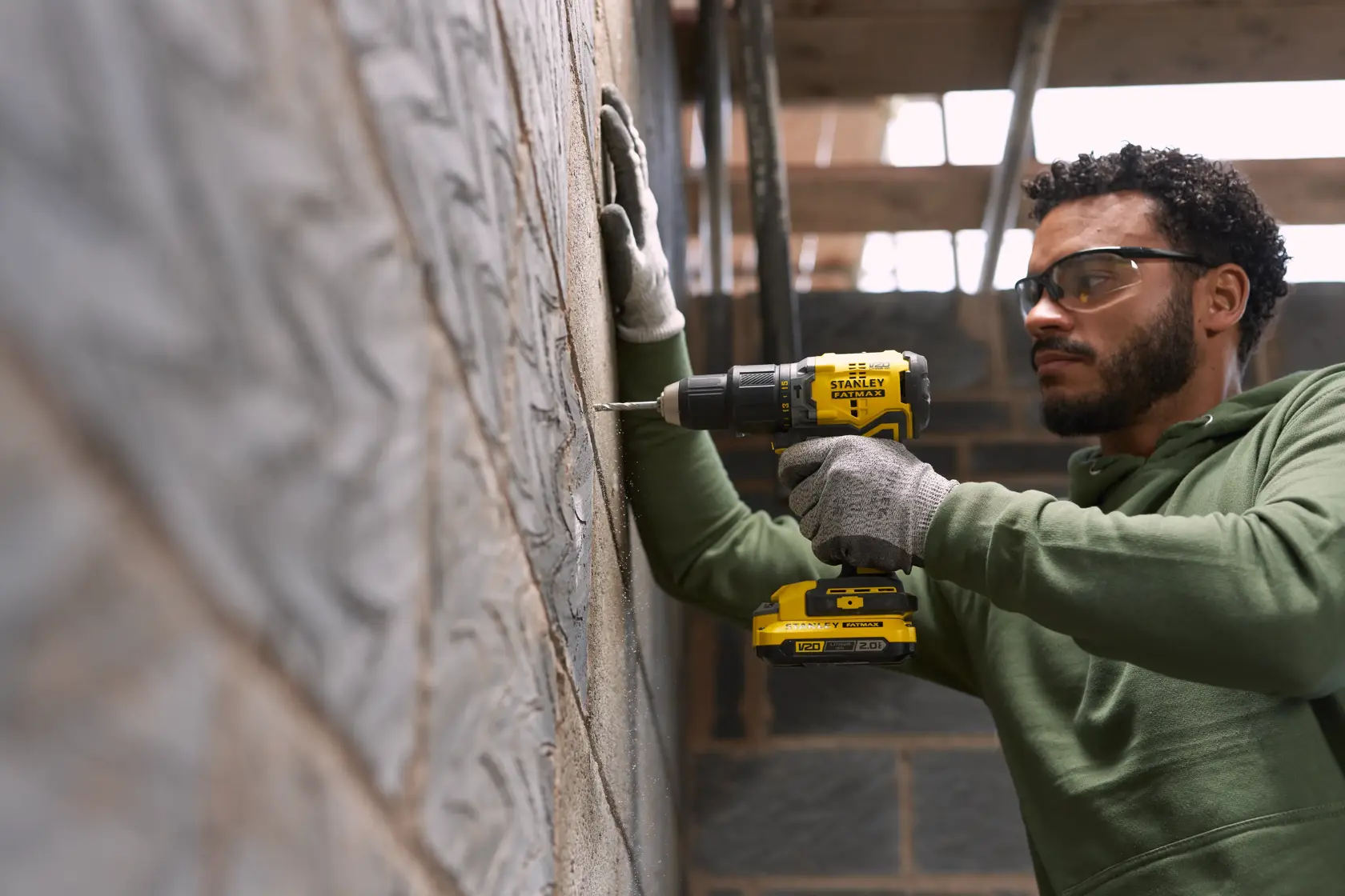Photo of STANLEY SFMCK461D2S cordless drill in use on a concrete wall at a construction site.