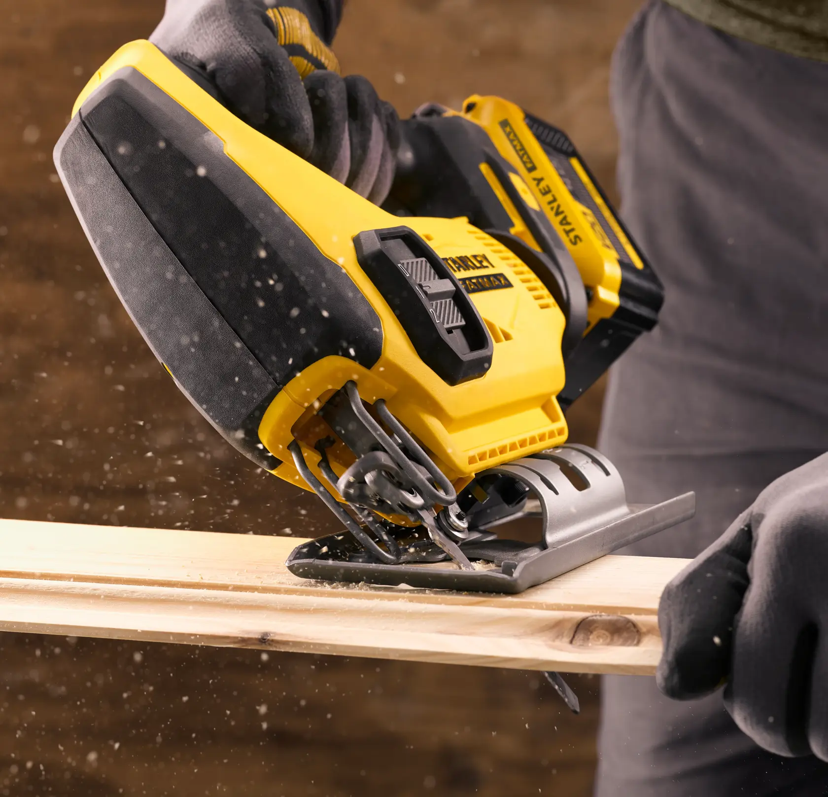 STANLEY SFMCS600M1K cordless jigsaw cutting wood, close-up view with sawdust particles in action.