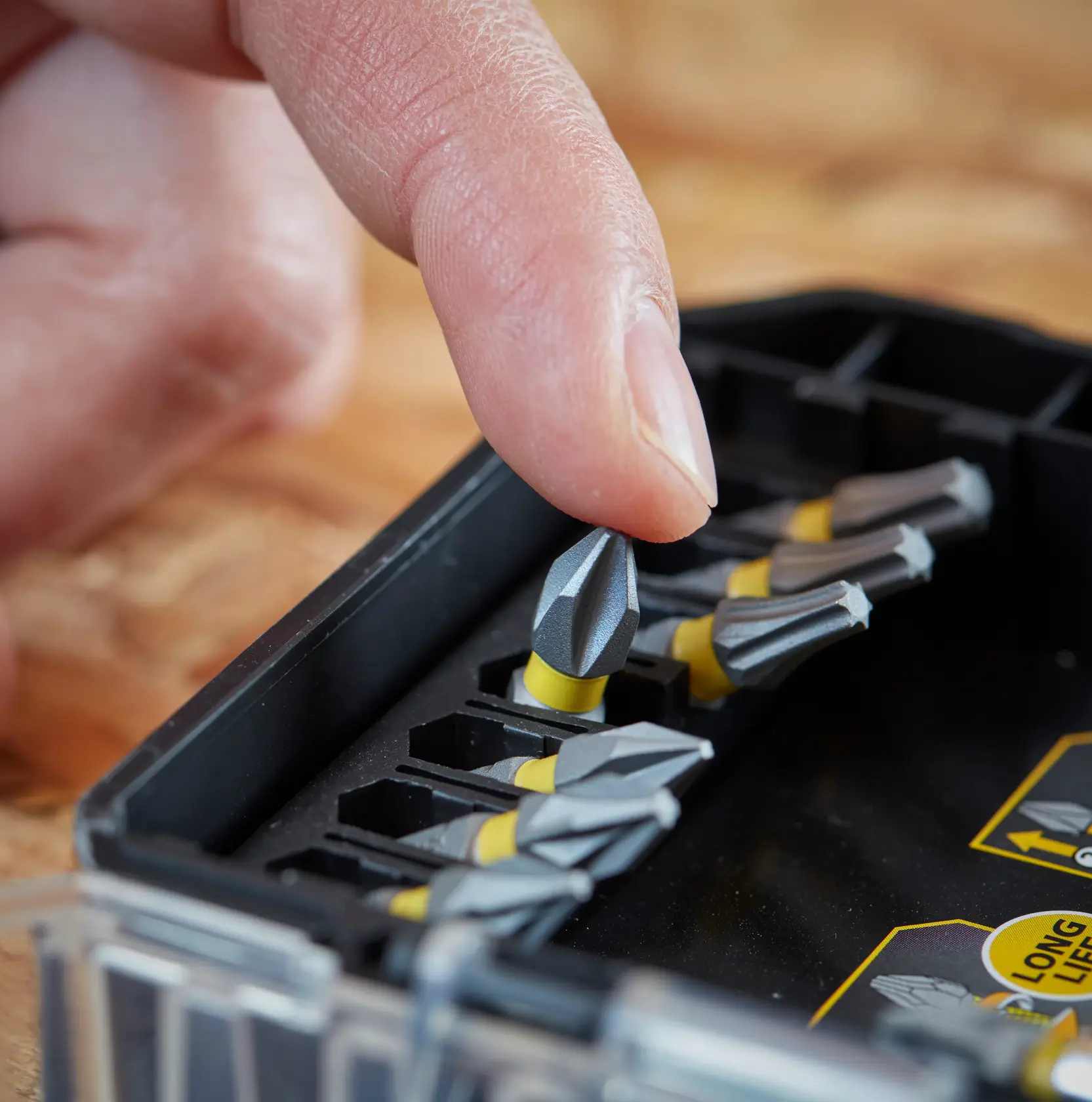 STANLEY STA88560 screwdriving bit set, close-up angle, finger picking up gray and yellow bit from case.