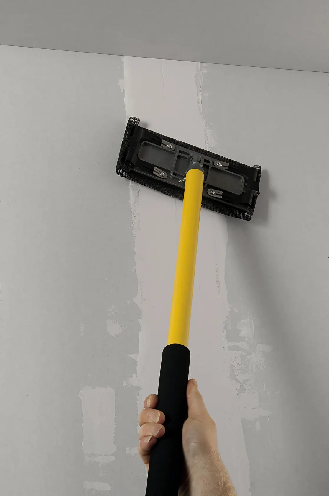 STANLEY STHT0-05928 drywall sander with yellow handle used on ceiling, close-up photography.