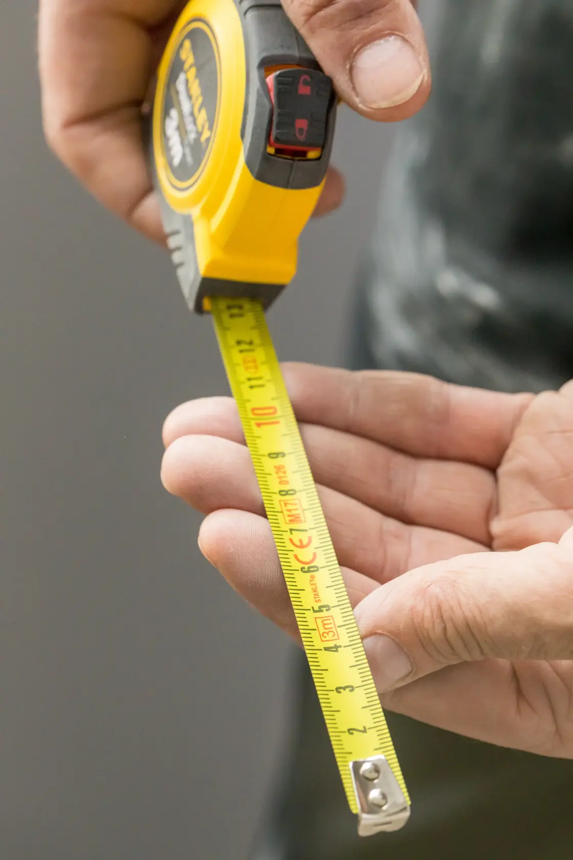 STANLEY STHT36806-0 tape measure, yellow and black, shown in hand extended for measurement.