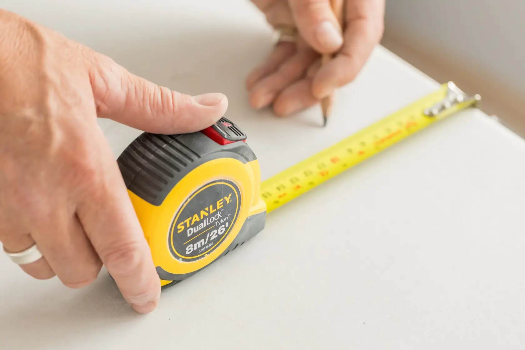 STANLEY STHT36807-0 measuring tape in use, yellow case with black accents, extended on a white surface.