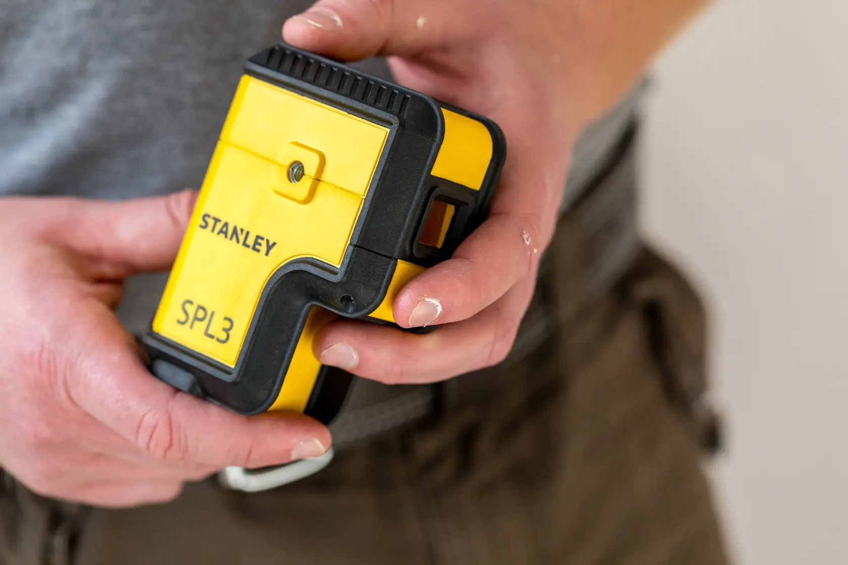 Photo of STANLEY SPL3 STHT77503-1 yellow and black laser level held in hand, front view.