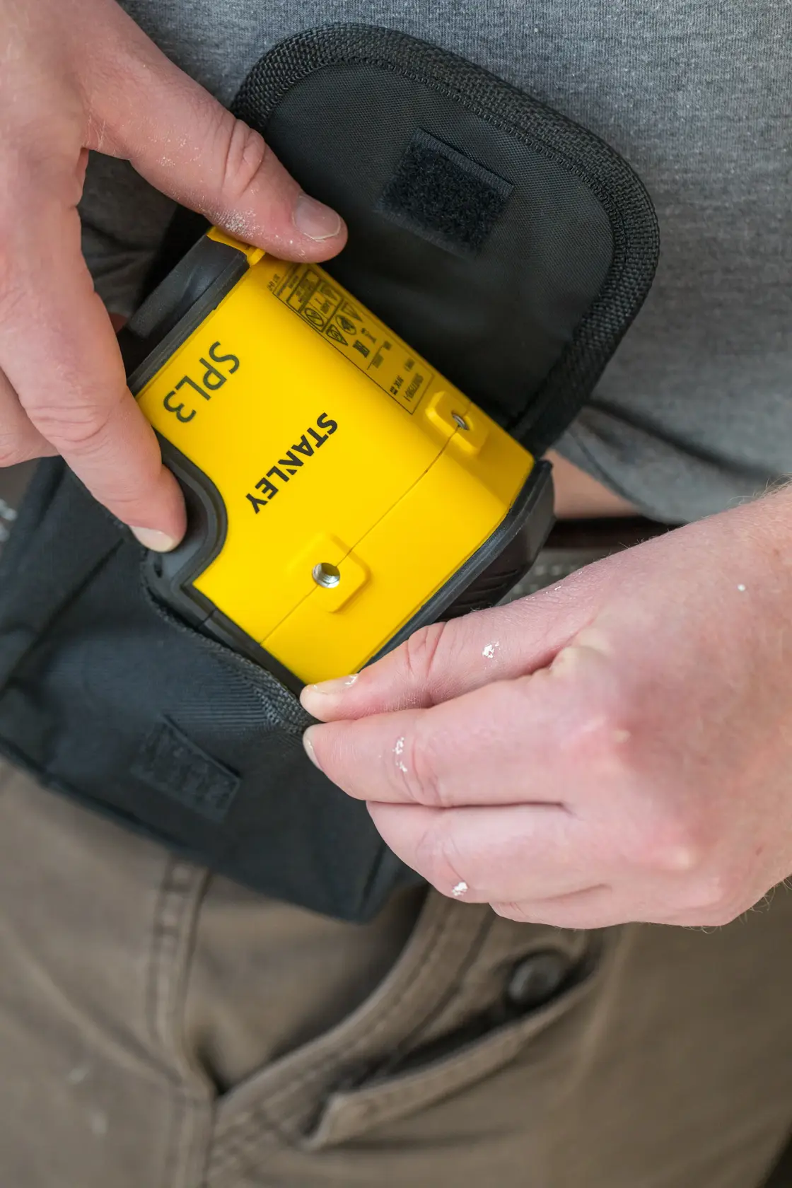 Photo of STANLEY STHT77503-1 yellow laser level being placed in black pouch, close-up view.