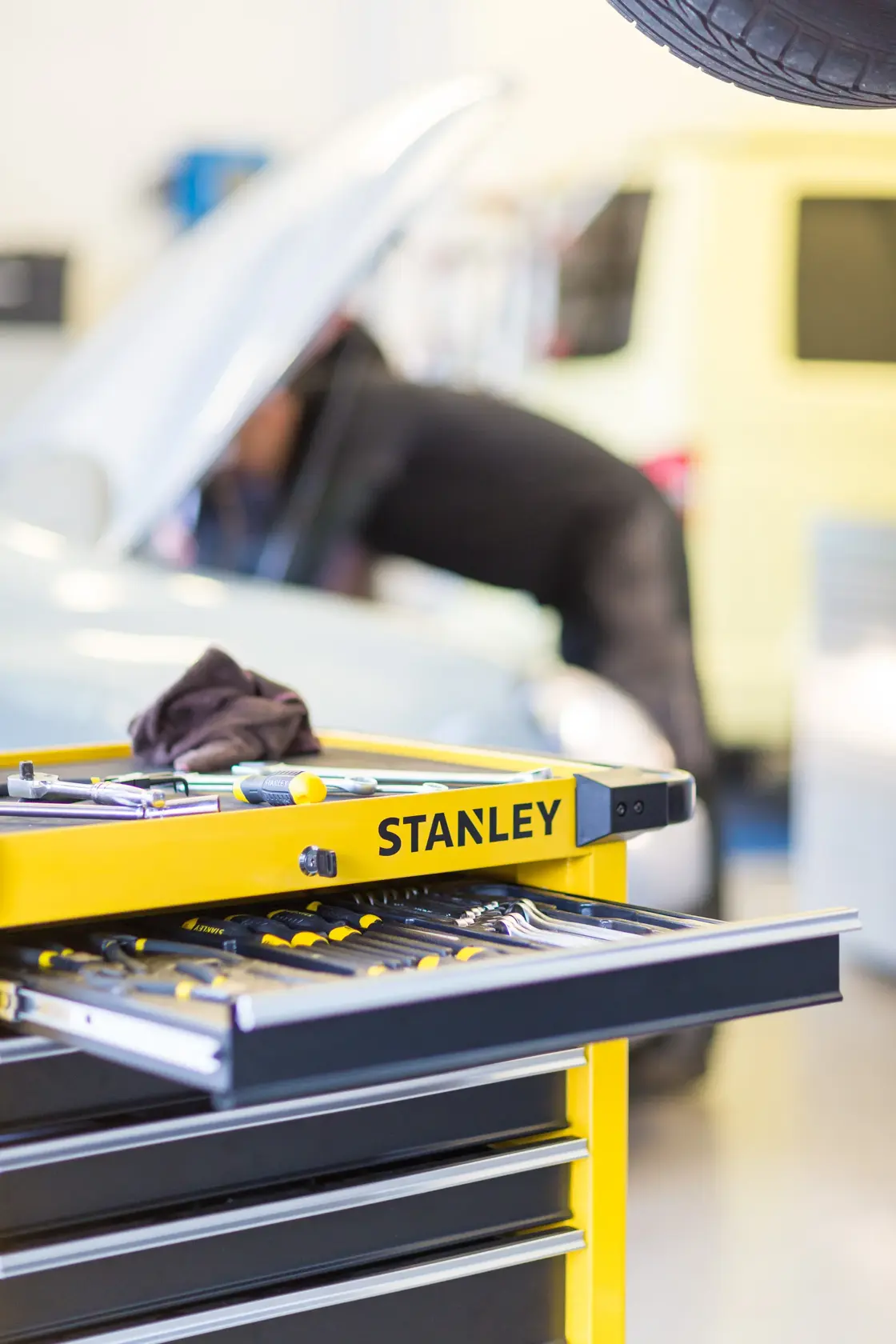 STANLEY STMT1-74306 tool chest with open drawer showing hand tools, garage workshop setting.