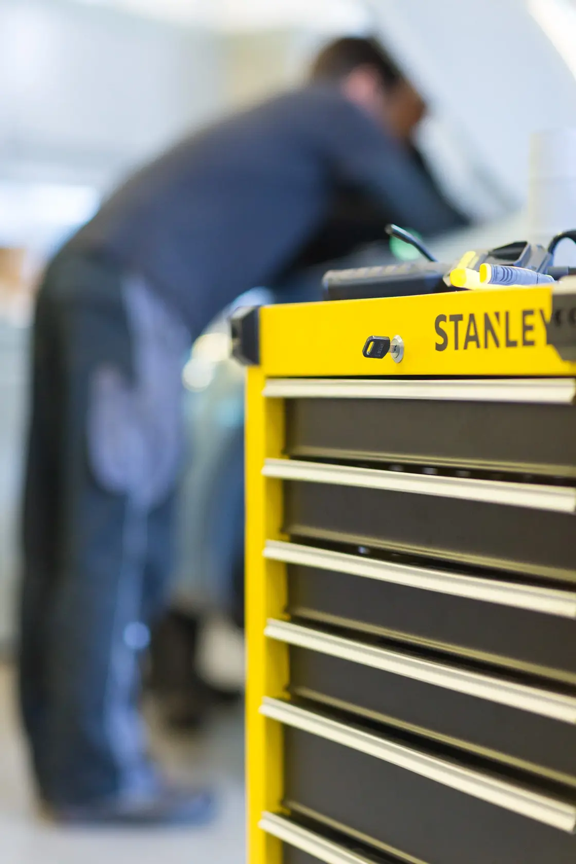 STANLEY STMT1-74306 tool chest with yellow front and metal drawers, photographed from side in workshop.