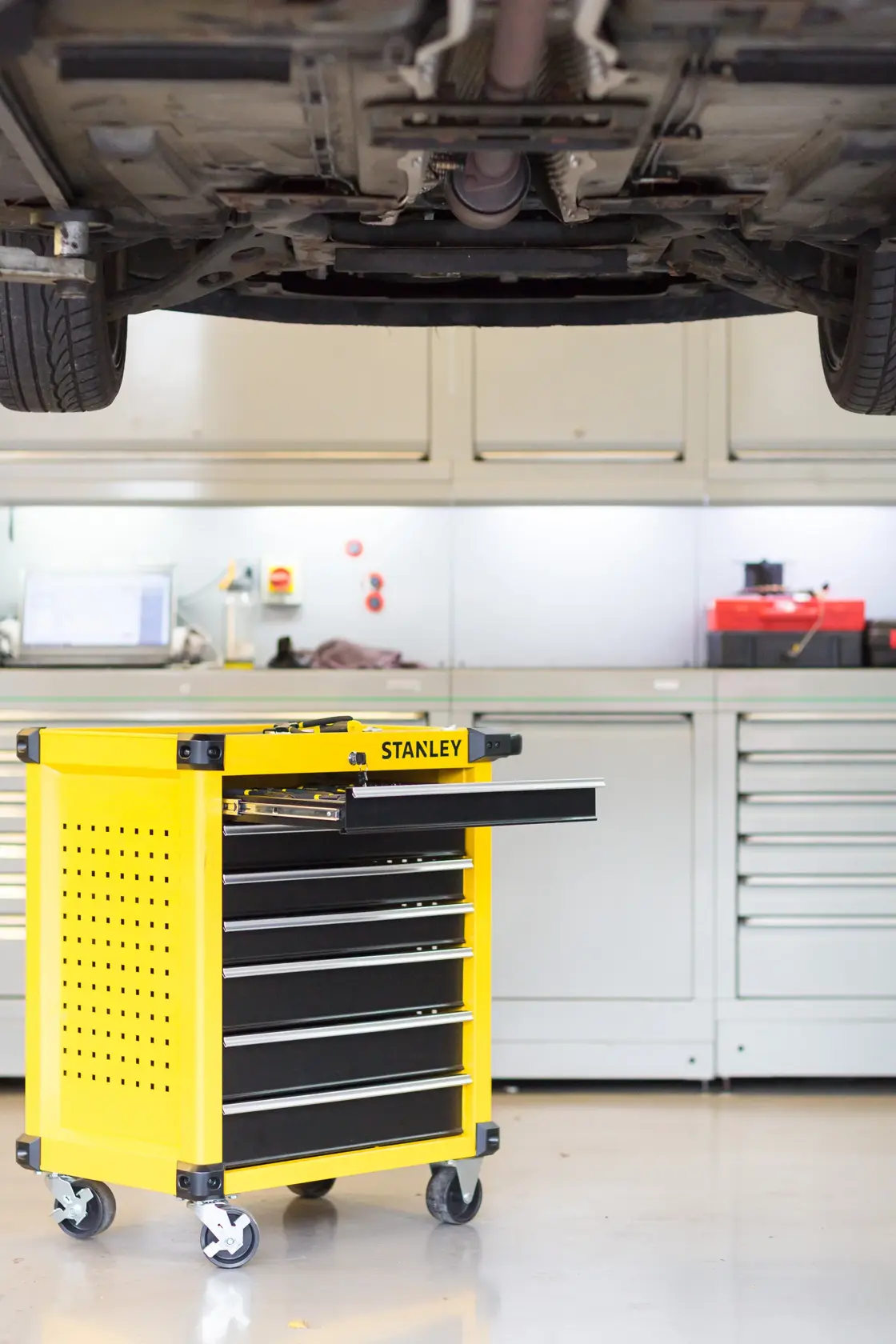 STANLEY STMT1-74306 yellow rolling tool cabinet with open drawer in workshop, side angle.