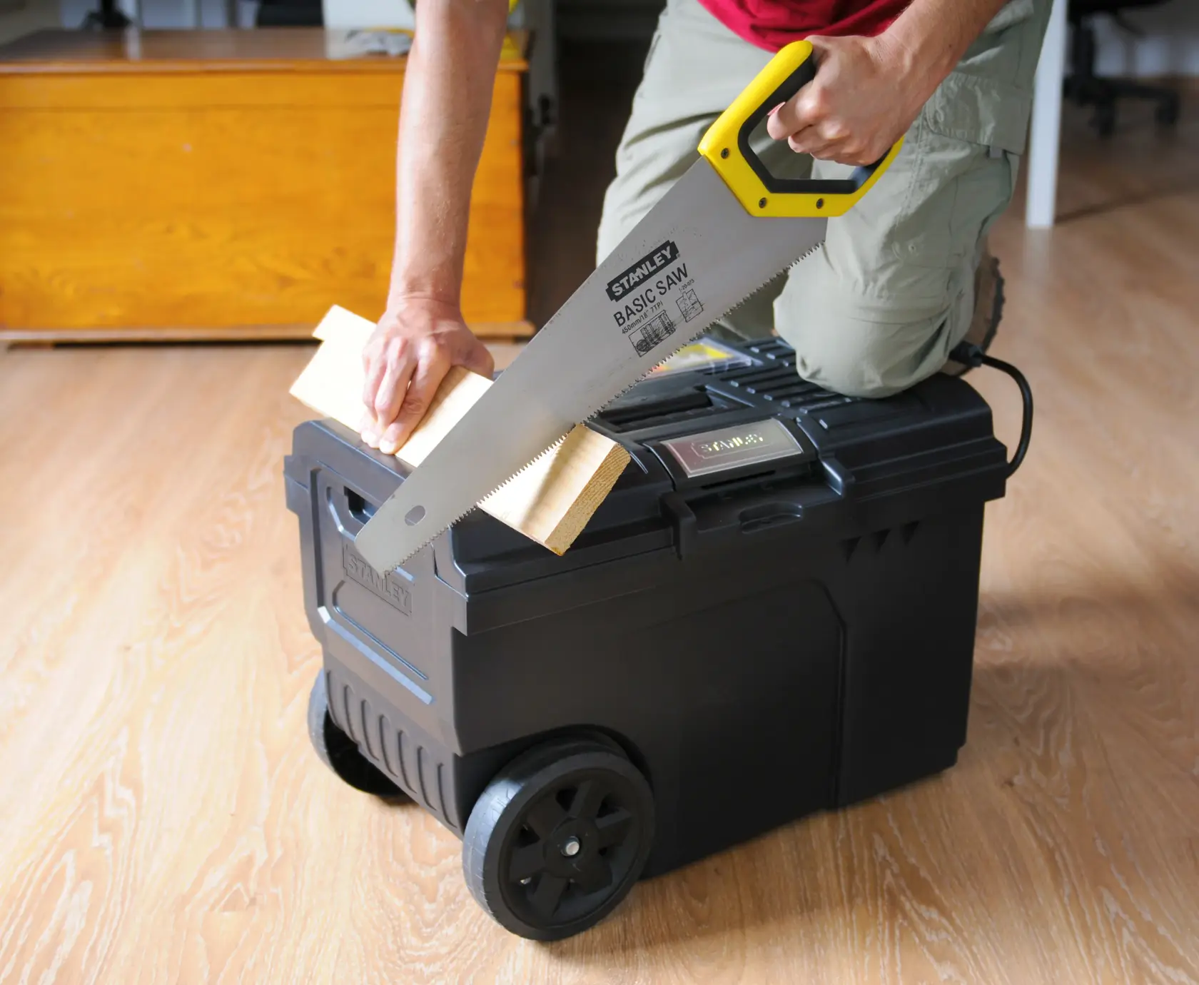 Photo of STANLEY STST1-70715 mobile toolbox used as a sawing support with hand saw and wooden plank.