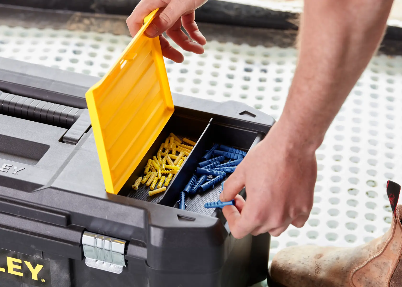 STANLEY STST82976-1 toolbox with open yellow lid showing compartments of blue and yellow wall plugs, close-up angle.