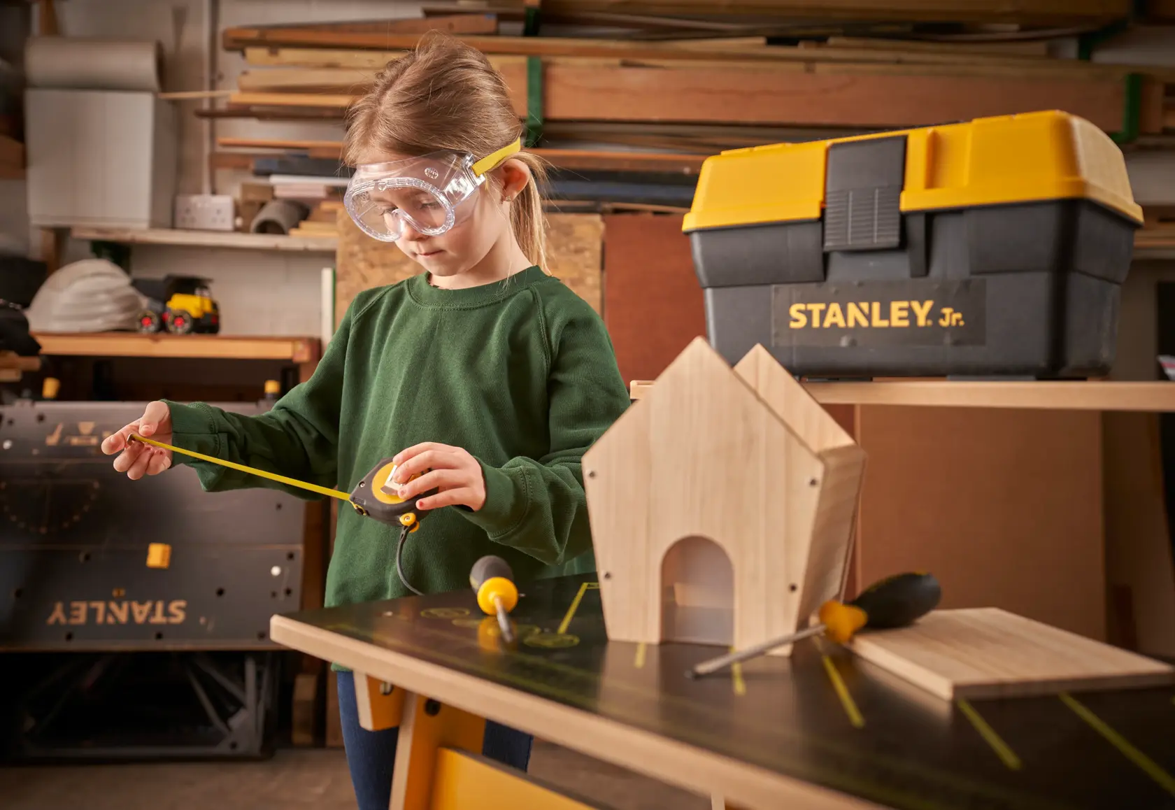STANLEY TBS001-05-SY toolbox with yellow lid and woodworking tools in workshop setting.