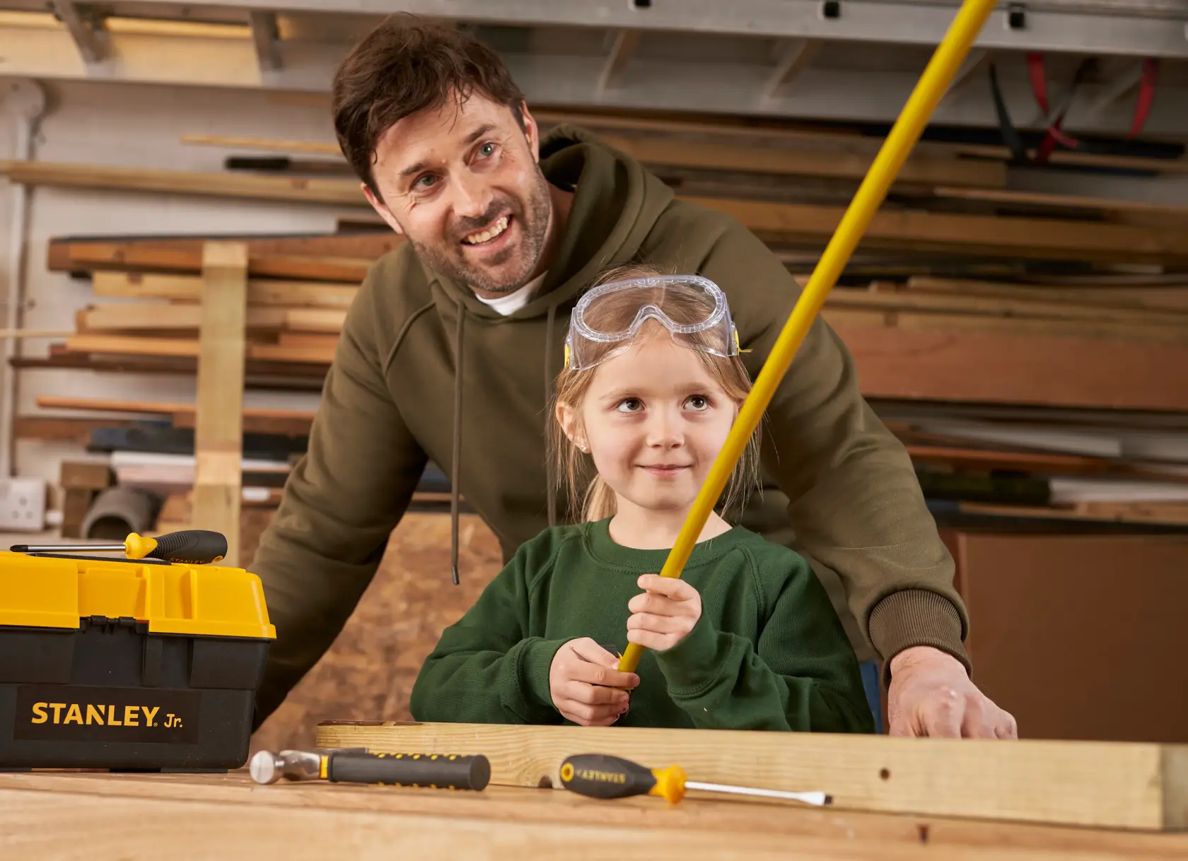 STANLEY TBS001-05-SY toolbox and tools with a child wearing safety goggles holding a yellow handle in workshop.