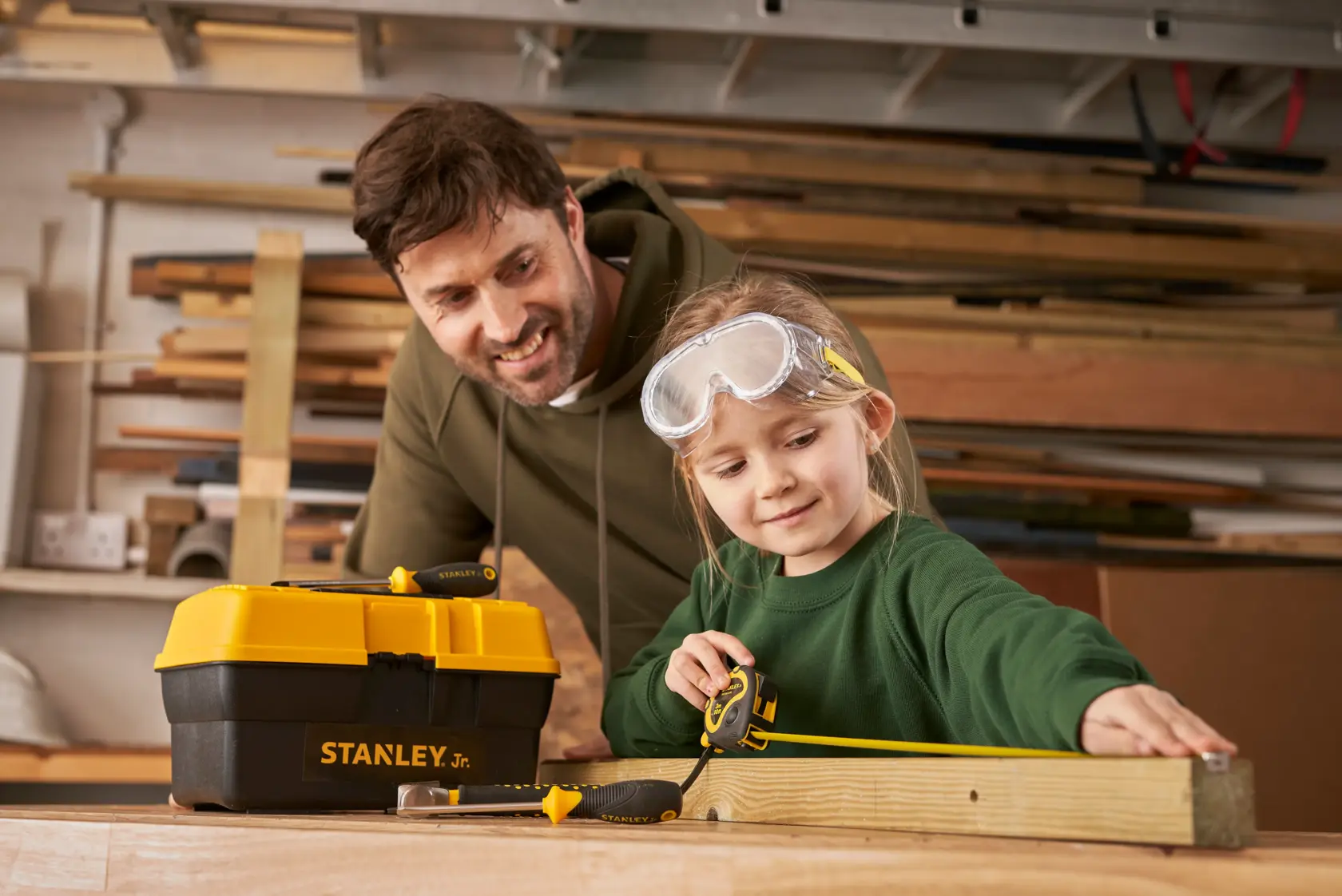 STANLEY TBS001-05-SY toolbox and tools with tape measure in woodworking workshop, side angle.