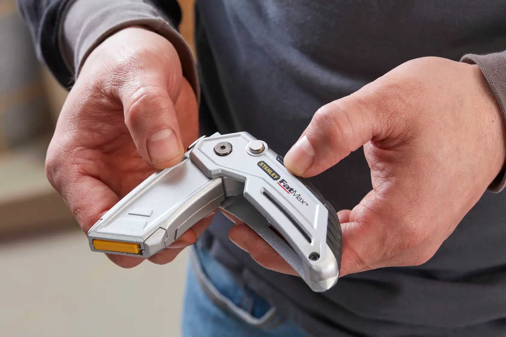 Photo of STANLEY XTHT0-10502 utility knife held in hand, silver folding design with visible logo.