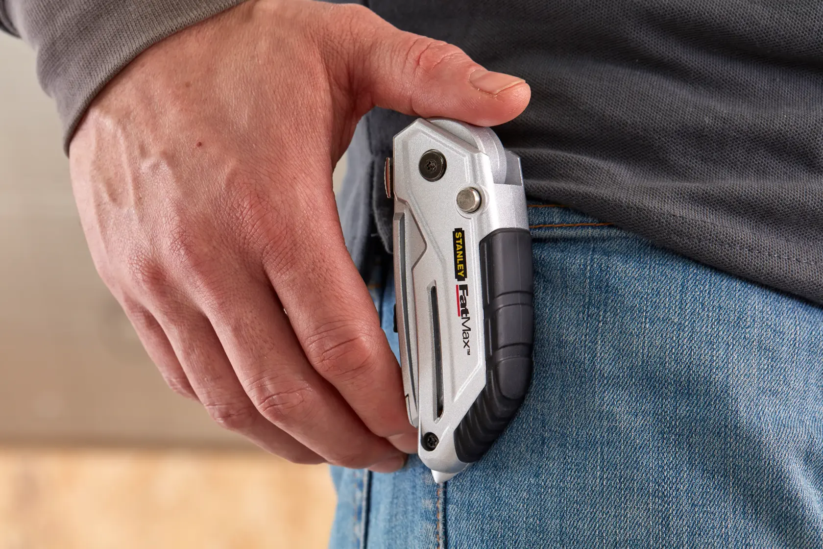 STANLEY XTHT0-10502 utility knife with silver and black handle clipped to jeans, close-up side angle.