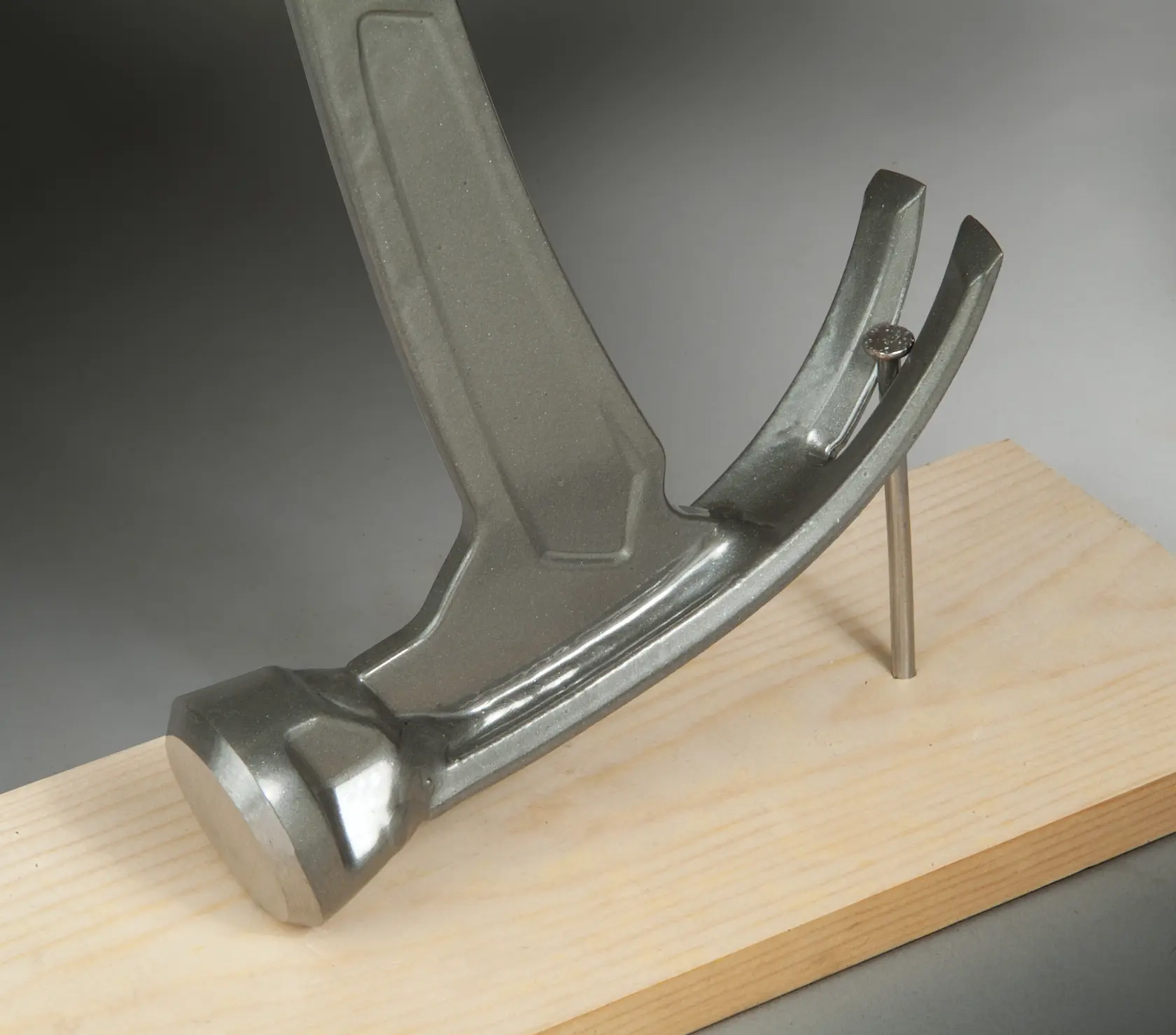 STANLEY XTHT1-51148 hammer close-up on white background with nail held in wood.