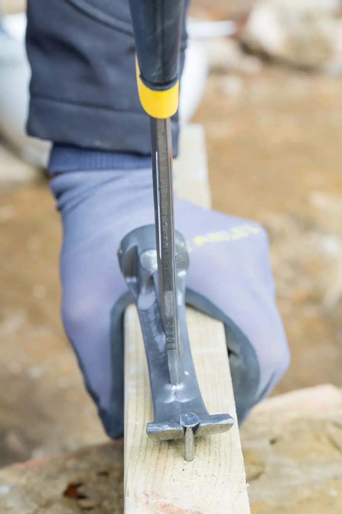 STANLEY XTHT1-51148 claw hammer removing nail from wood, close-up photo of gloved hand in use.